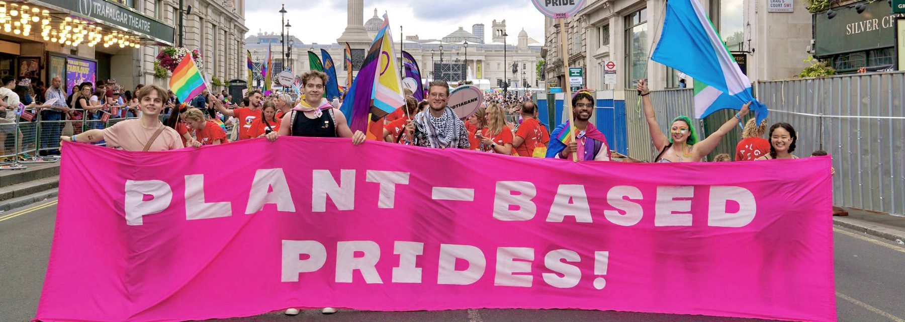 Plant-Based Prides marchers carrying a pink banner reading 'Plant-Based Prides!' through central London